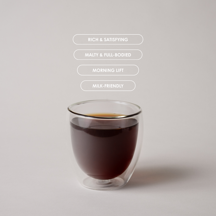 Glass of dark liquid with text describing its qualities on a light gray background