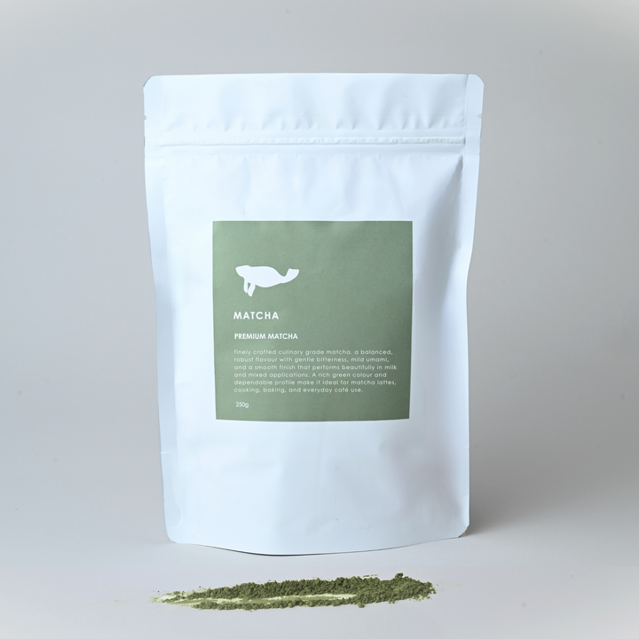 White packaging of matcha green tea powder with a green label on a light gray background.