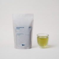 Tea package labeled 'Lemongrass and Ginger' next to a glass of green tea on a white background